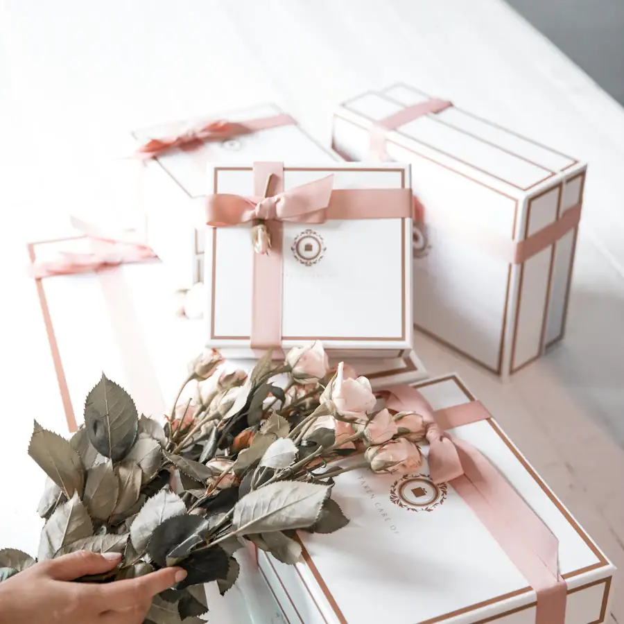 White gift boxes tied with blush ribbon beside dried roses