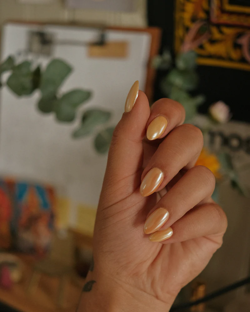 Almond nails in metallic gold chrome with eucalyptus behind
