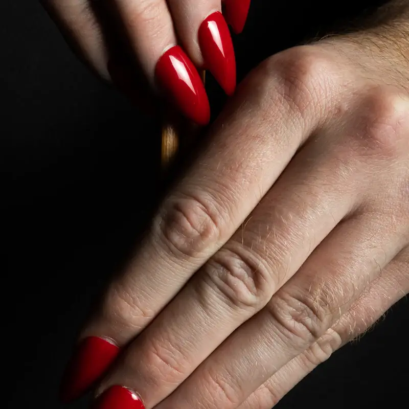Glossy long red nails against a dark background