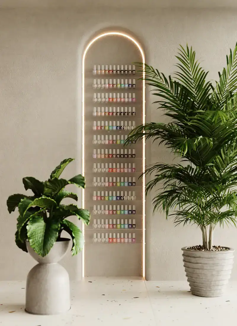 Arched, softly lit polish wall between two potted palms in a calm cream studio