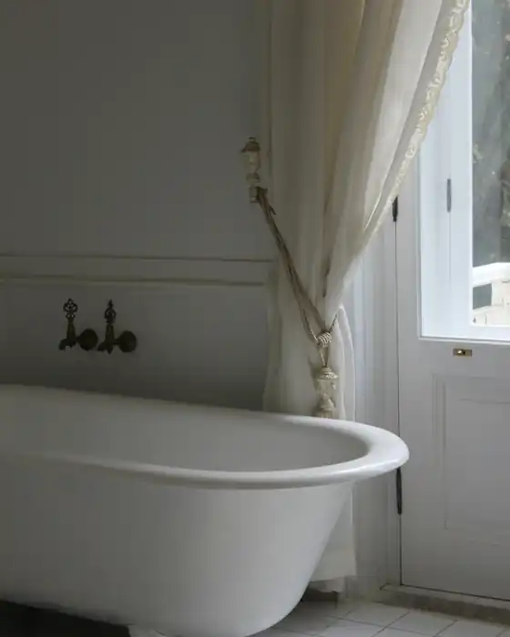 A freestanding claw-foot bath beside a tall window