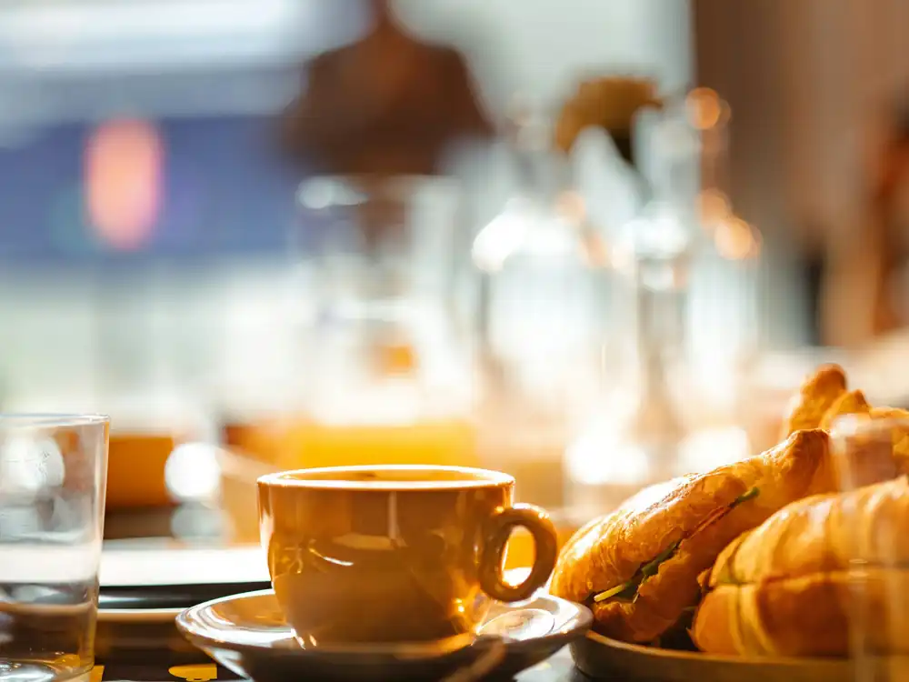 Fresh croissants and a cup of coffee on a breakfast table in soft morning light