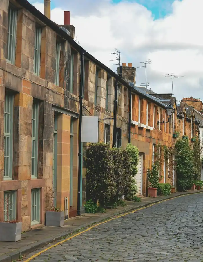 A curving cobbled mews lane lined with stone cottages and climbing plants