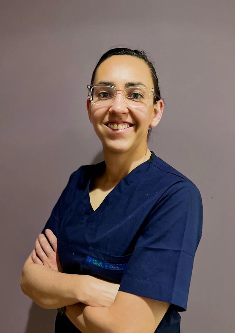 Dr. Paula Medina in navy scrubs with arms folded, smiling