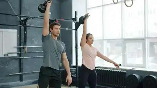 Two people doing kettlebell swings side by side