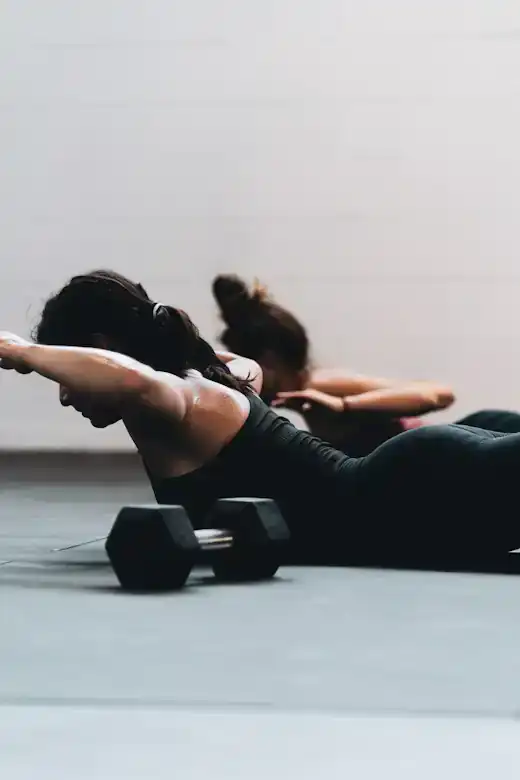 Two people stretching on mats next to small dumbbells