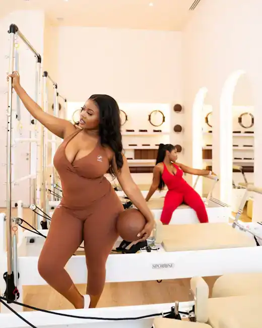 Two women using reformer towers in a cream studio