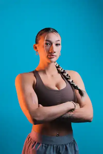 Portrait of coach Lena Ortiz, arms crossed, against a blue backdrop