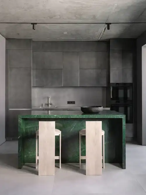 Kitchen with a green marble island and two pale timber stools