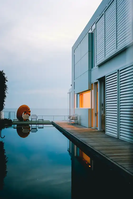 Contemporary home with timber screens beside a still reflection pool facing the sea