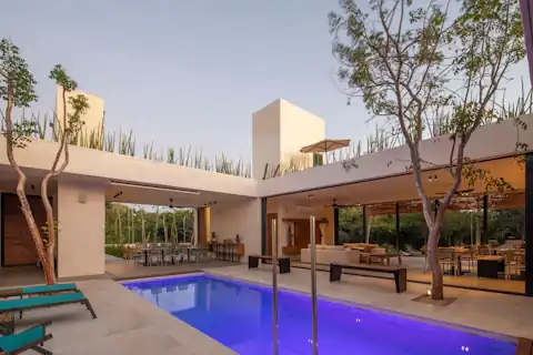 Courtyard house with a lit pool and outdoor lounge under the trees