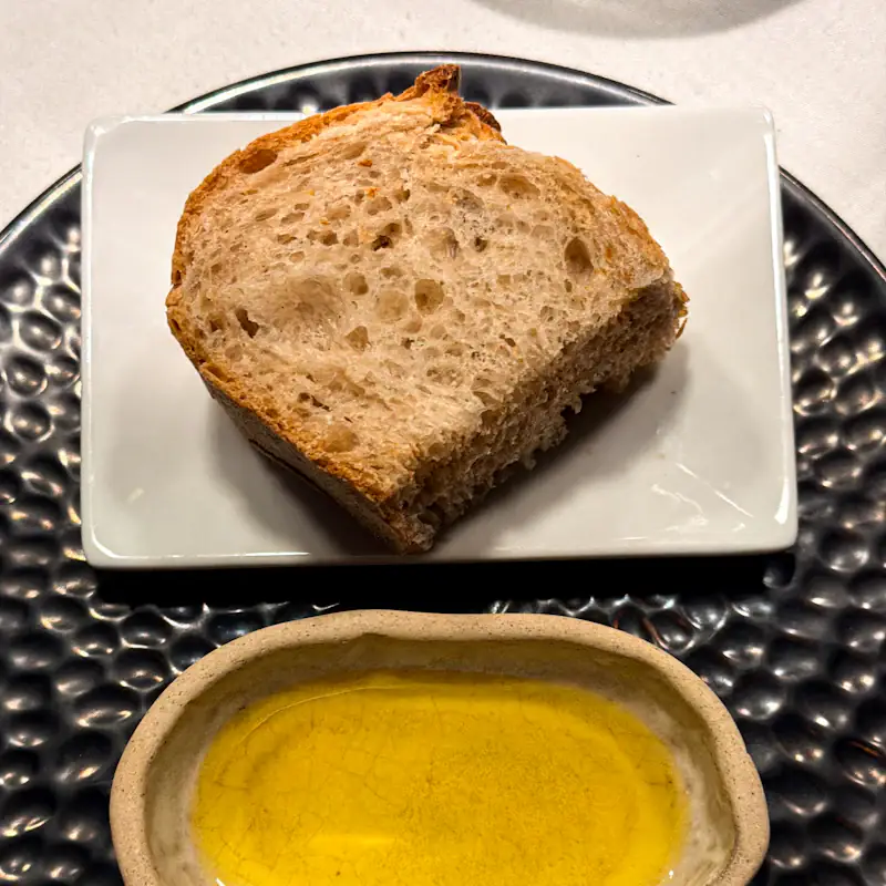 Slice of sourdough beside a dish of golden olive oil