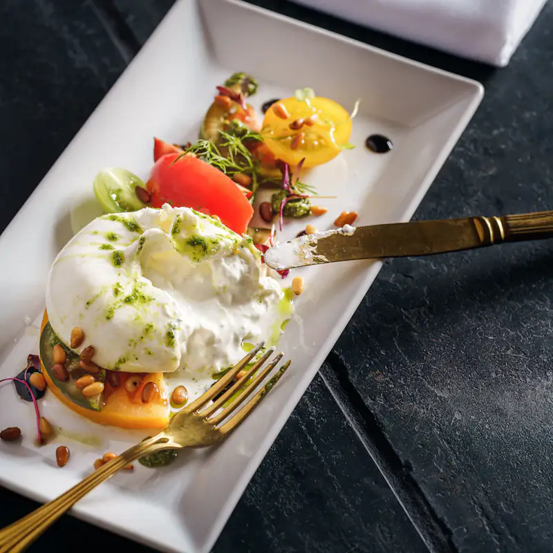 Burrata with tomato and pistachio on a white plate