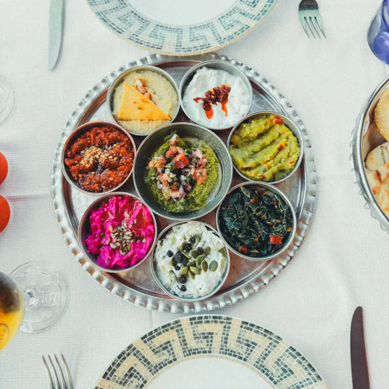 Silver tray of colourful dips including beetroot, hummus and herbs
