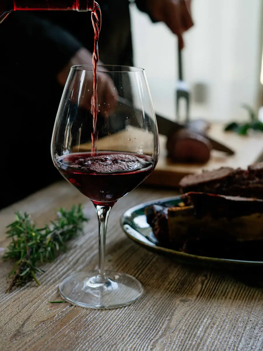 Red wine being poured into a glass on a candlelit wooden table
