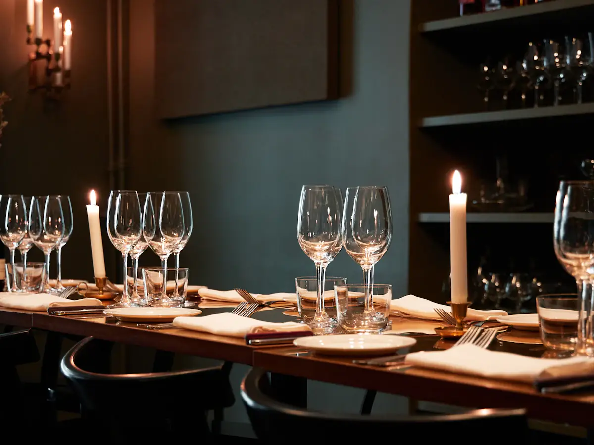Long candlelit table set with wine glasses in a dark green private dining room